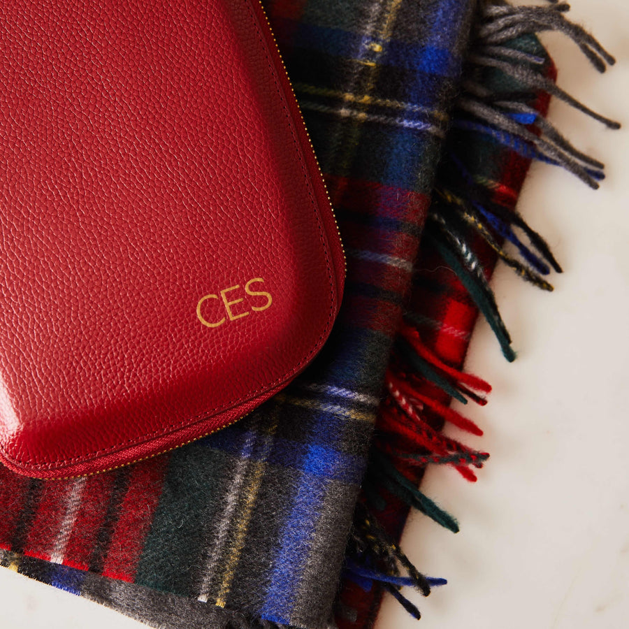 a red clutch overlaying a gray and blue plaid cashmere scarf