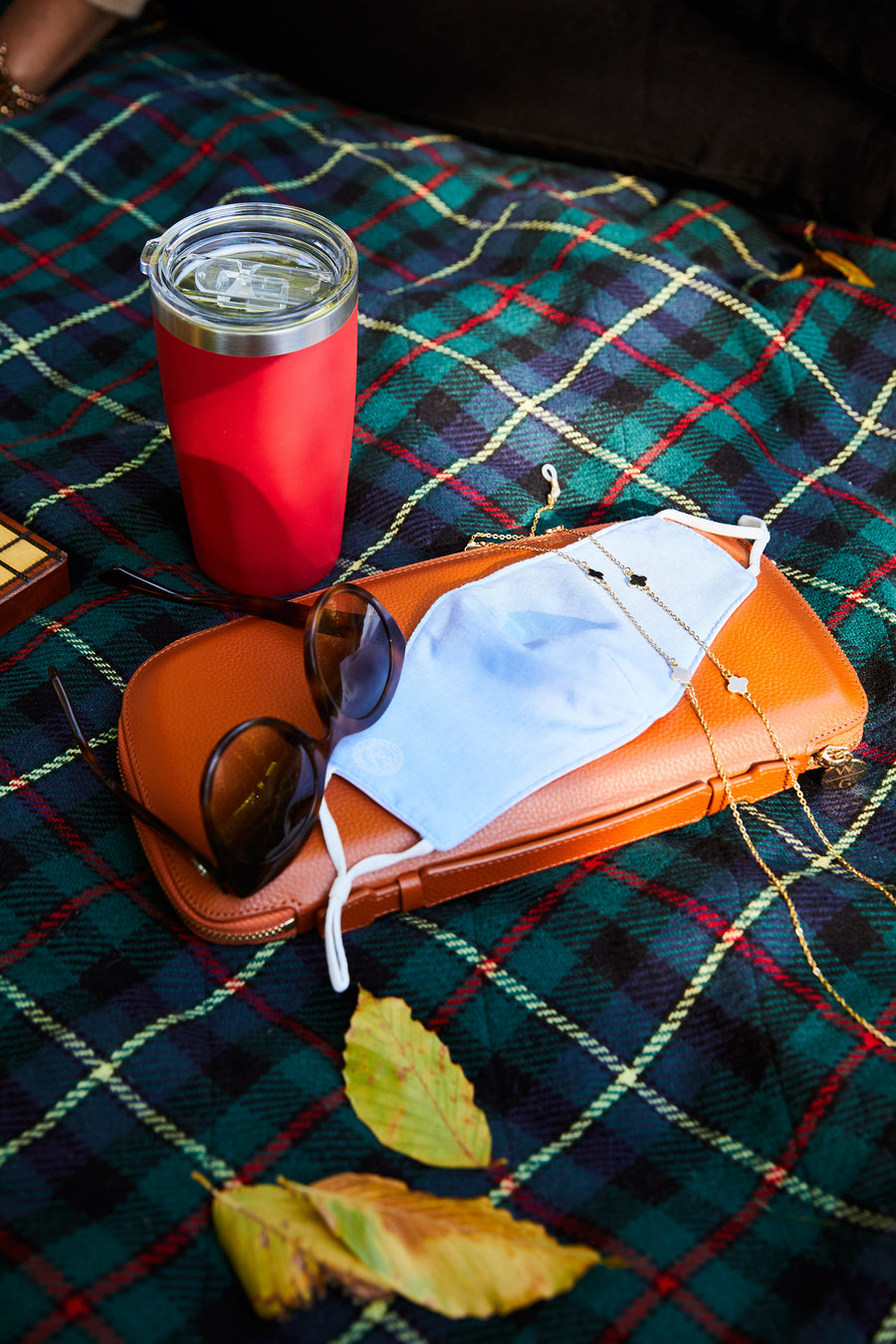 Blue linen mask on plaid blanket on top of our essential clutch, 