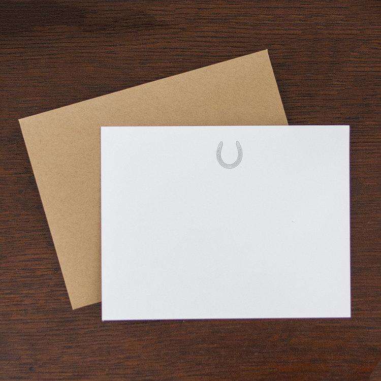 white flat notes with gray horseshoe on the top center and a brown envelope